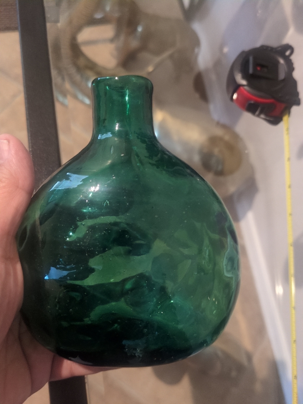 Vintage Hand-blown bulbous emerald green glass bottle with a narrow neck.